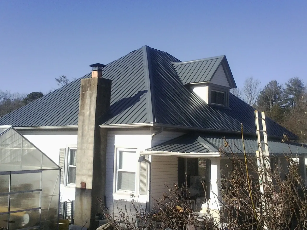Dark blue standing seam metal roof on a white farmhouse with dormer — Slate & Tile Roof Repair by Roofing Brothers in Reed Point