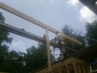 Carpenter setting a ridge beam over a new addition frame — Ice Dam Removal by Roofing Brothers in Reed Point