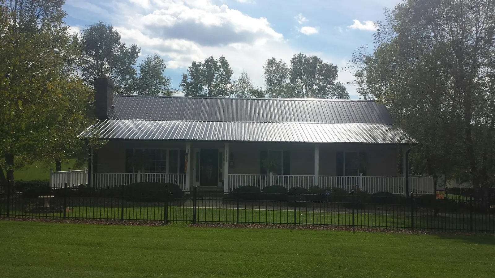 Gray metal roof on a brick ranch with a full width front porch — Gutter Guard Installation work by our crew in Reed Point