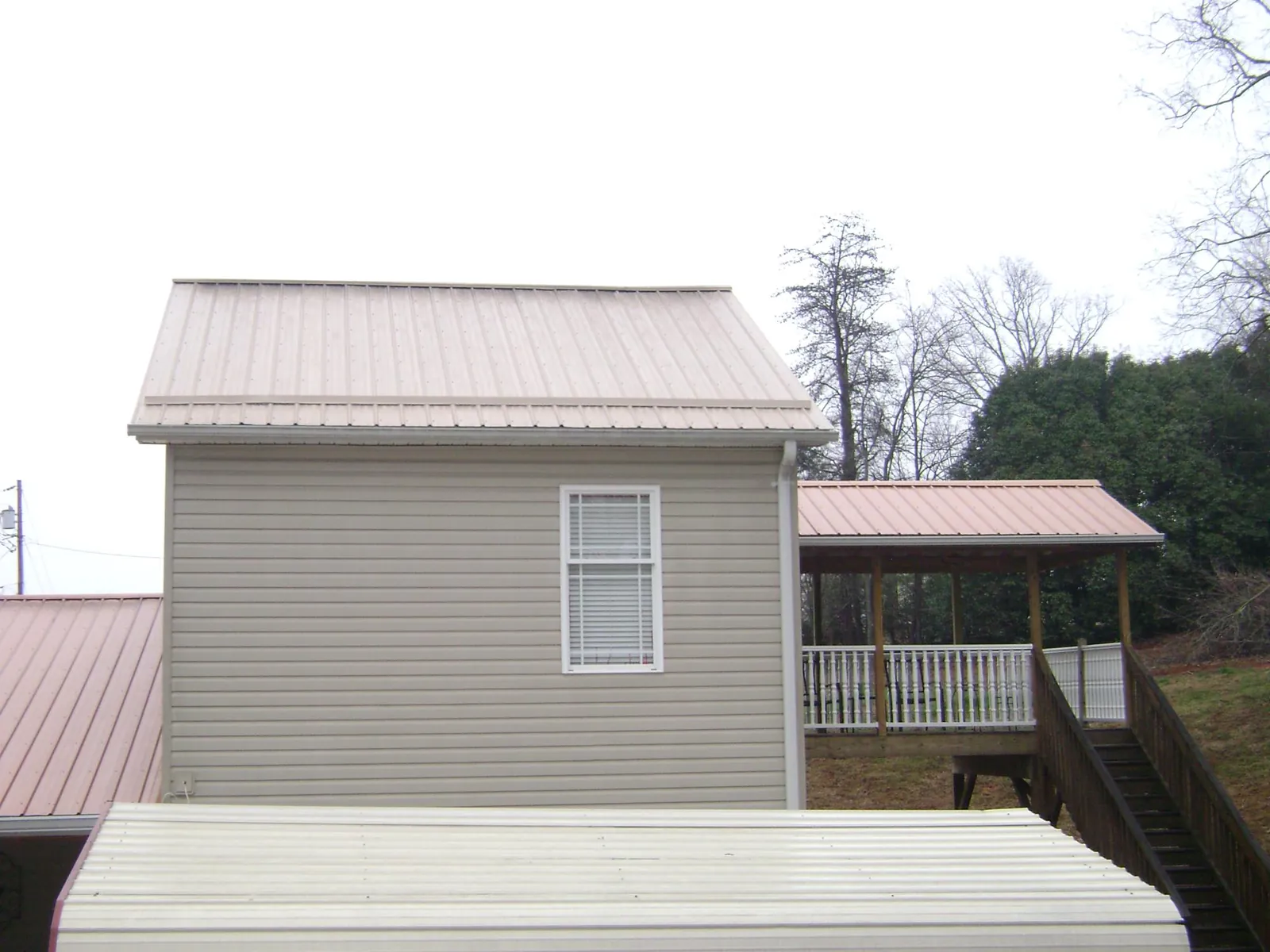 Tan metal roofs on a two story addition and attached porch, from a Roof Replacement job in Reed Point