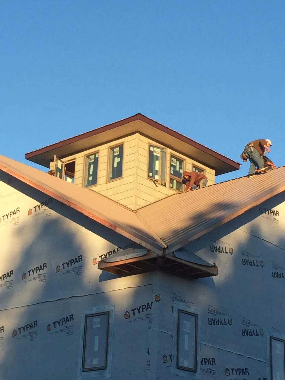 Roofers working around a rooftop cupola on a new metal roof at sunset — Roof Waterproofing in Reed Point by Roofing Brothers